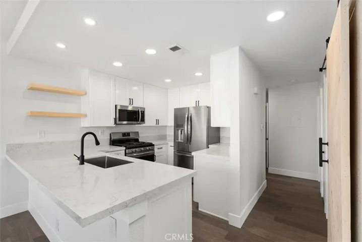 Remodeled kitchen complete with recessed lighting, breakfast bar, floating shelves