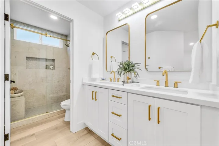 Designer dual vanity and tile shower with gold glass enclosure and matching appointments