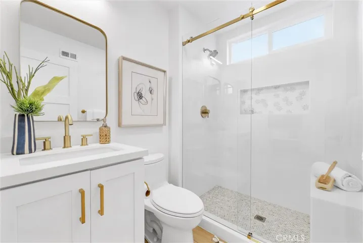 Secondary bath with beautifully tiled bright white shower and gold touches