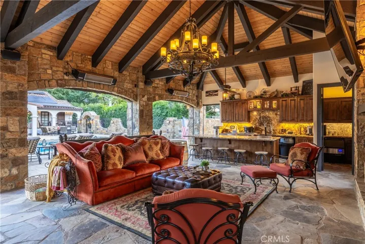 Open beam construction with a chandelier and flagstone decking. There is a full bar with commercial refrigeration, a full size wine refrigerator, commercial ice maker, a stunning fireplace, heaters, ceiling fans, and a half bathroom.