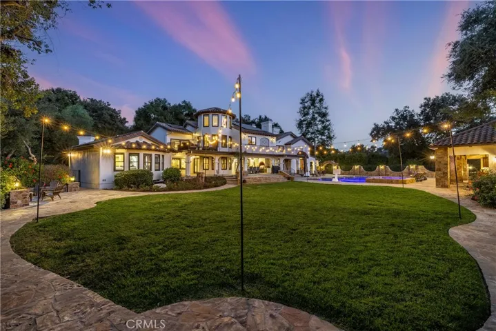 Elevation from the back grass area featuring a perimeter walkway, a parklike setting with a fire pit and more.