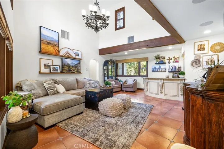 Family room off the kitchen offering a soaring ceiling with a chandelier, windows overlooking the backyard, and a built-in bar.