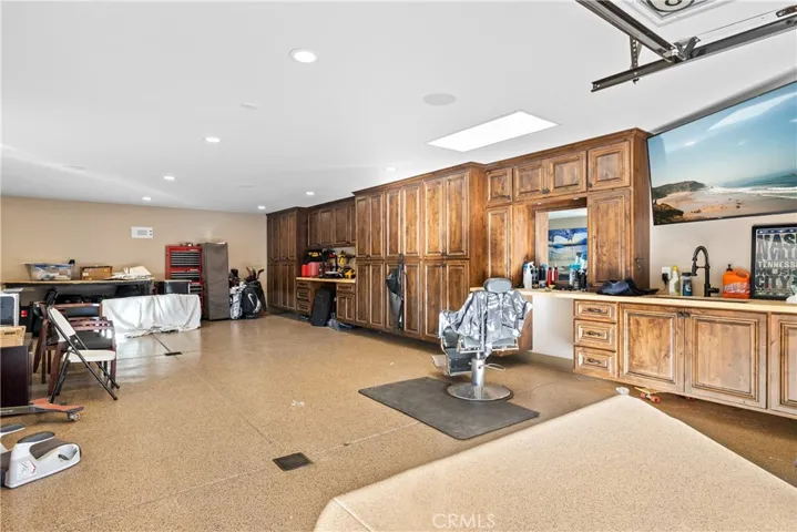 Inside the four car garage features full length built-in cabinets with a barber station, plumbed for compressed air, surround sound, LED lighting, and epoxied floors.