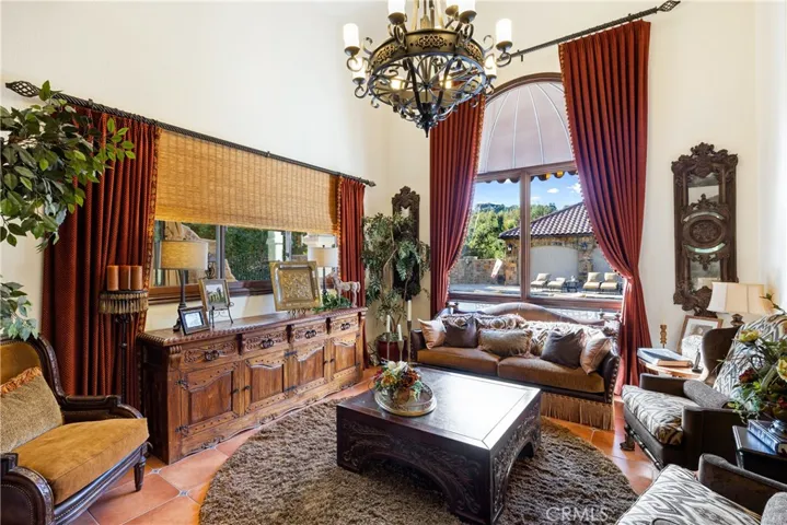 Formal living room with chandelier, floor to ceiling drapery, and views to the backyard.