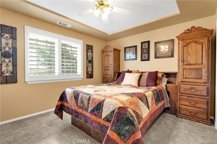 Large hall bedroom with plantation shutters, hand textured ceilings with tray inset in two tone paint. This room hosts a queen bed suite with room to spare. Carpet is only four years old and is still like new.