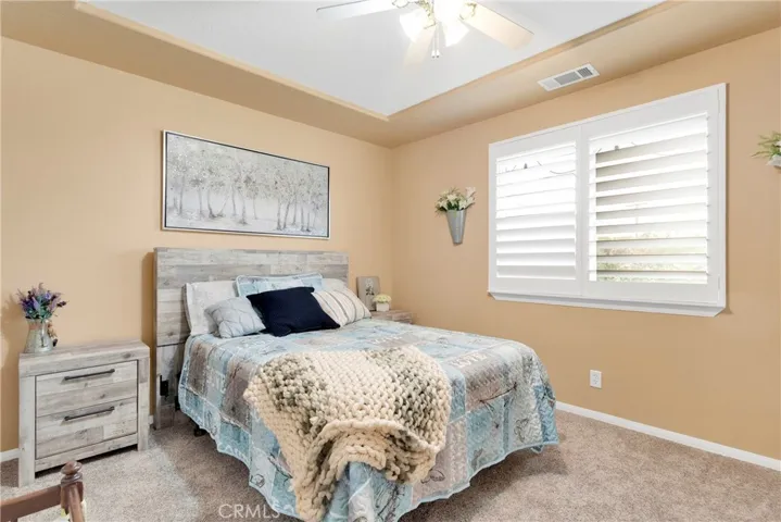 Hall bedroom with plantation shutters, tray ceiling in two tone paint, and plush carpet. Carpet is only four years old and is still like new. This room hosts a Queen bed with room to spare.