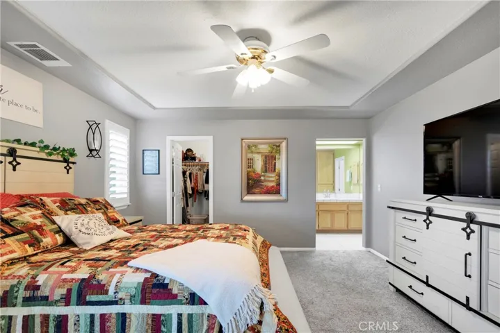 Large primary bedroom suite with plantation shutters, private access to the large covered patio, tray ceiling with two tone paint.