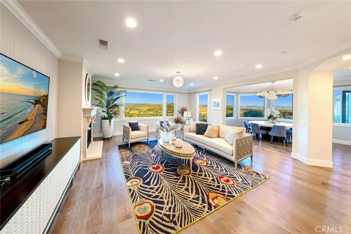 AN EXPANSIVE FAMILY ROOM HIGHLIGHTING DESIGNER SILK WALLPAPER, A GRAND FIREPLACE SURROUND, MOTORIZED BINDS/SHADES & PANORAMIC VIEWS