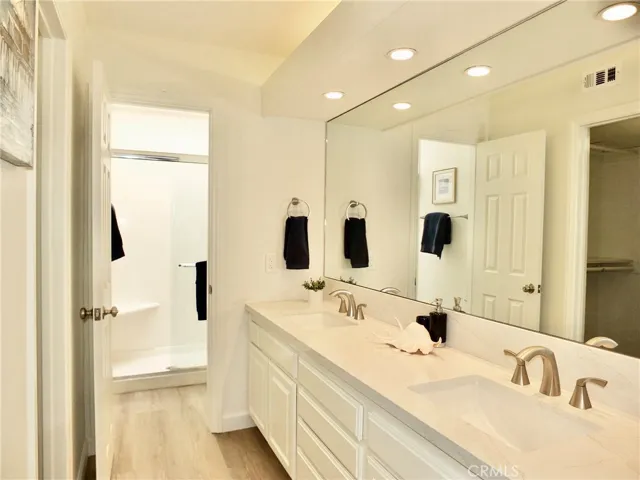 New Quartz double sinks in primary bathroom & comfort level toilet behind door next to stall shower