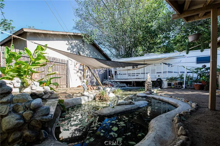 The large fish pond is next to the travel trailer.