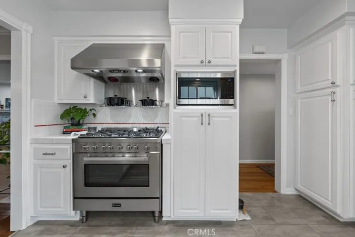 Newer 5 burner oversized gas range with stainless hood, pot shelves for convenience.  Microwave area built into cabinet frees up counter space