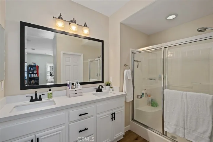 Remodeled bathroom with white cabinets, quartz countertop, new faucets and a custom mirror.