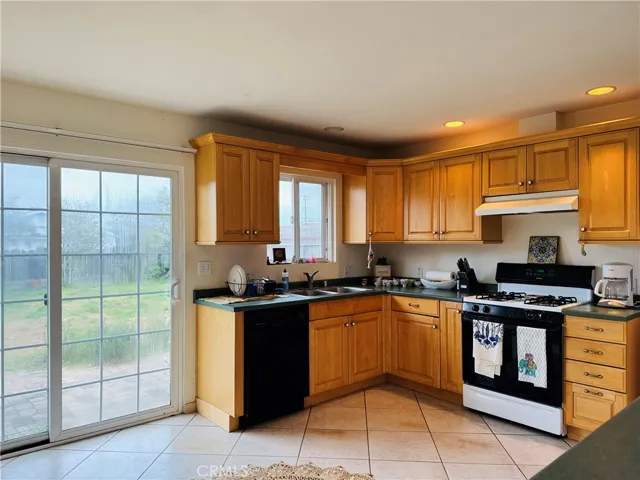 Bright kitchen with newer oak cabinets and tile flooring.
