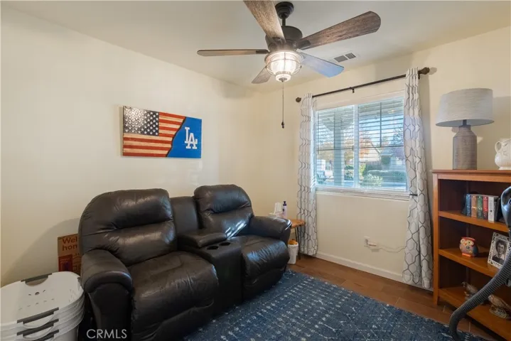 Guest bedroom with wood plank tile flooring, faux wood blinds, ceiling fan