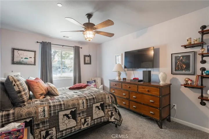 Guest bedroom with faux wood blinds, ceiling fan and upgraded carpet.