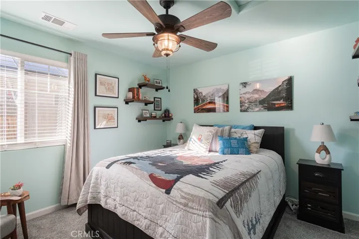 Guest bedroom with faux wood blinds, ceiling fan and upgraded carpet.
.