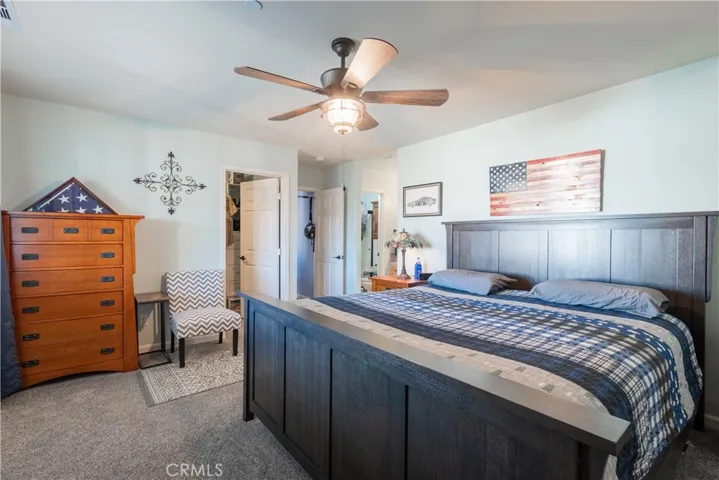Owners' suite with walk in closet, ceiling fan and upgraded carpet.