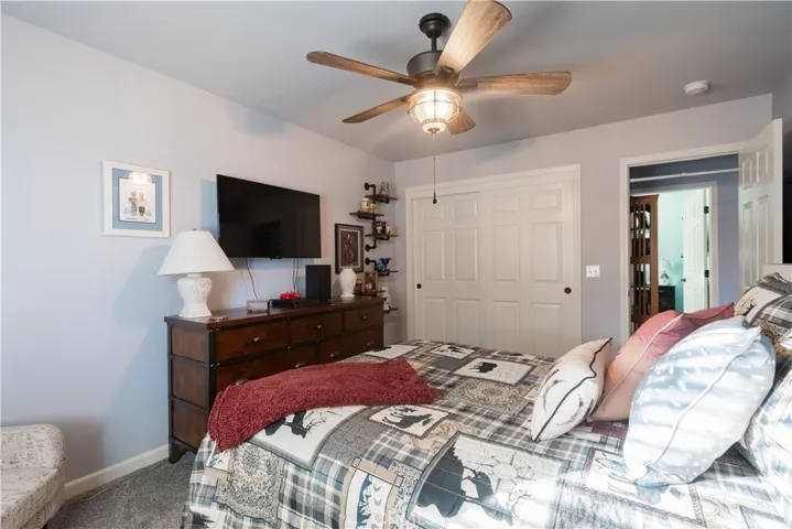 Guest bedroom with faux wood blinds, ceiling fan and upgraded carpet.