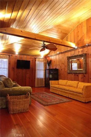 Comfy living room off the kitchen. Ceiling fans. great breezy windows. Window coverings, maple floors, pine walls preserved from original structure.  3 bedrooms are off of this room, and the Fireman's loft.