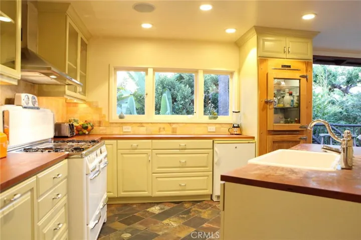 This darling kitchen features a vintage gas stove, dual ovens.  Teak counters, island sink and work area.  Klondyke refrigerator.  Stone floors, self closing drawers, ocean breezes and view.  Attached to patio and stairs to lower level.