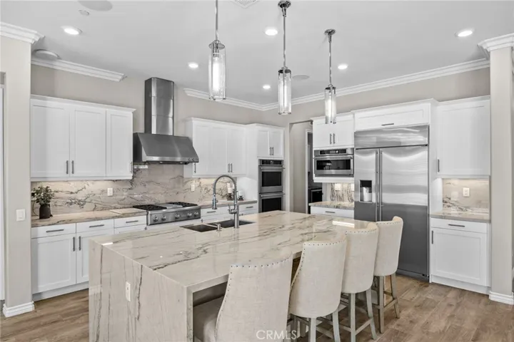 Chef's gourmet kitchen with Monogram stainless-steel appliances and double oven. Quartzite countertops and backsplash, and elegant lighting.