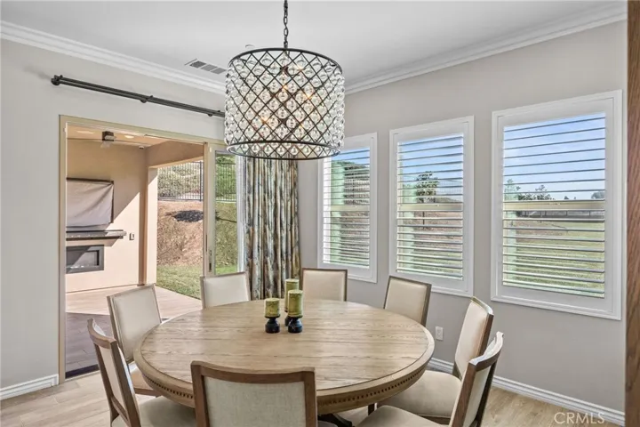 Kitchen nook with full view of adjacent CA room. Designer chandelier and plantation shutters.