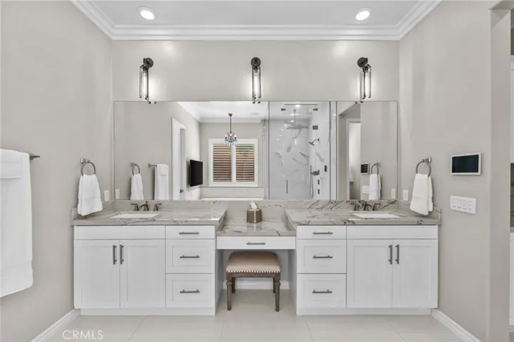 Double sinks in primary en-suite bathroom with quartzite countertops and vanity area.