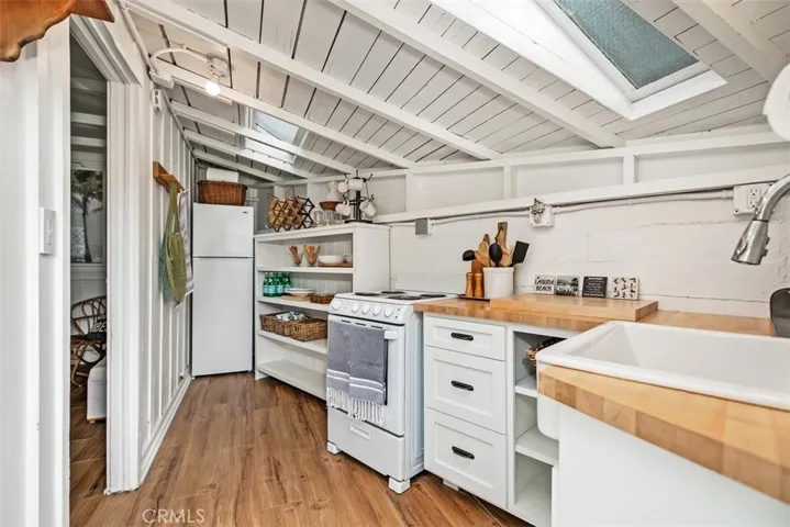 Kitchenette with range , refrigerator, and butcher block wood counters.
