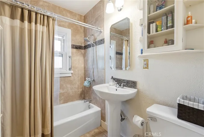 Remodeled bathroom with pedestal sink and tiled shower enclosure.