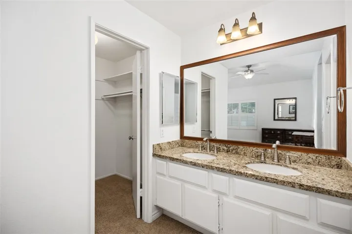 Primary Bathroom with Dual Sinks and Granite Counters and Walk-In Closet