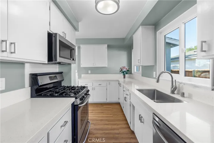 View of the kitchen from the living room. Pendant light fixture is new. Two sets of windows provide ample sunlight.
