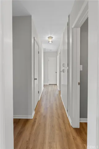View of the hallway from the entry way. Closet door provides additional room for storage. Walls were freshly painted. Cabinets refinished with new handles/hinges. Light fixtures in hallway are new as well. Straight ahead is the door to the furnace. From there the hallway turns left and ends at the Master bedroom.