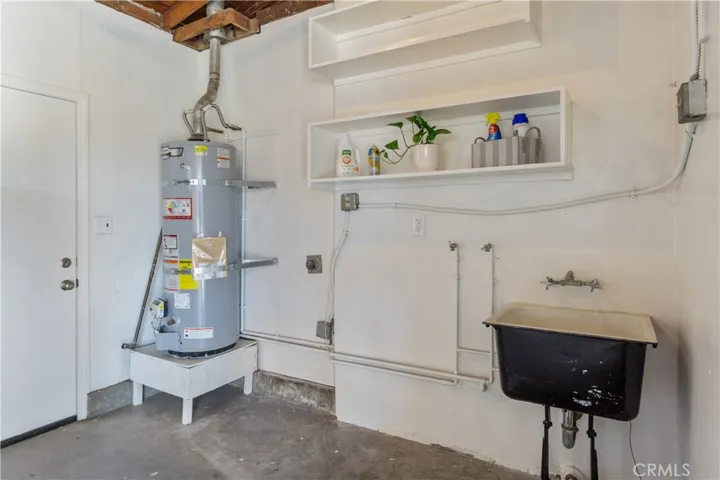 Laundry room/water heater is in the garage area off the breakfast nook from the kitchen. Hook ups for washer/dryer are provided. Laundry sink gives added convenience as well as the shelves above to store laundry items. Door leads to the side yard facing west.