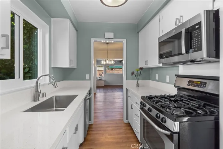 View of kitchen looking towards the living and family room areas. Easy access for hosting various events. New quartz countertops were installed. Stainless steel farmhouse sink and faucet are new. New vinyl planks were recently installed as well. Microwave and dishwasher are new.