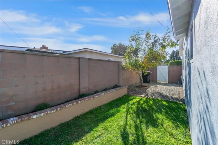 Side yard on the east side of the home. A birch tree is just outside the 3rd bedroom window. Flower beds along the block wall fencing provide added space for plants, flowers or vines.