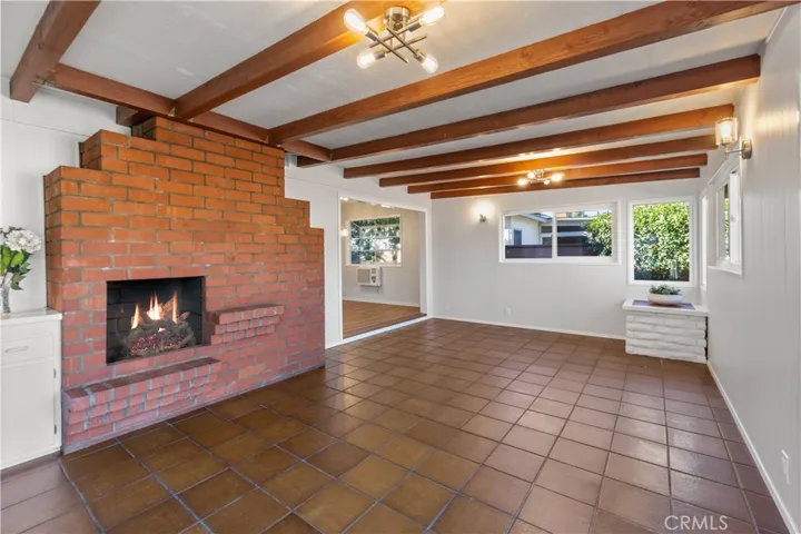 The family room is just off the living room. Beamed ceiling and fireplace adds to the rooms charm. Tile floor enhances the rooms character. Lovely space to entertain family and friends. A large throw rug would add to the rooms ambiance. Windows are double pane and new. To the left of the fireplace is a small desk which provides extra cabinets for storage. New quartz countertop was installed, with new desk lamp.