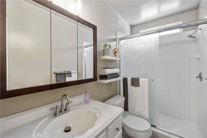 3/4 bath is right off the entryway and across from the 1st bedroom. Shelves and brush nickel faucet are new. Cabinets were refinished with new knobs/handles. New vinyl planks were installed. Walk-in shower has some space. Light fixture above mirror is new. Bathroom was freshly painted.