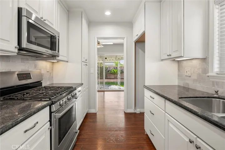 Upgraded kitchen with beautiful white cabinets, black granite countertops, stainless Bosch 6 burner range, oven and microwave/vent.