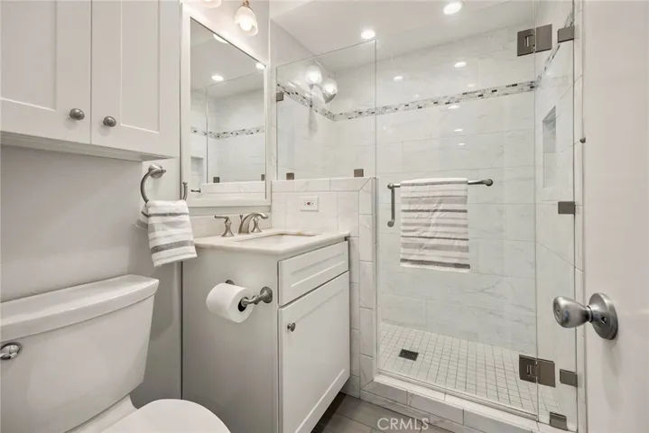 Entry bath with upgraded walk in tiled shower, new framed mirror,  and newly painted cabinets
