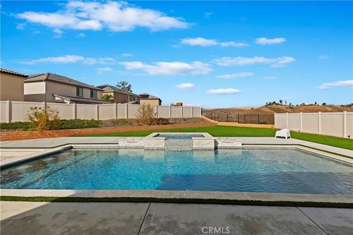Pool has swim step with a place for umbrella and on the left you can see built-in stools for hanging out over the fire pit area