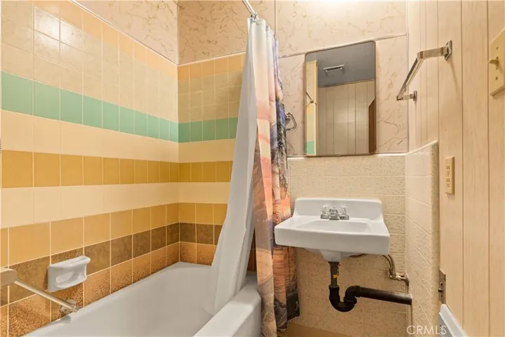 Full view of the sink, tub/shower and a wall heater to take the chill out.