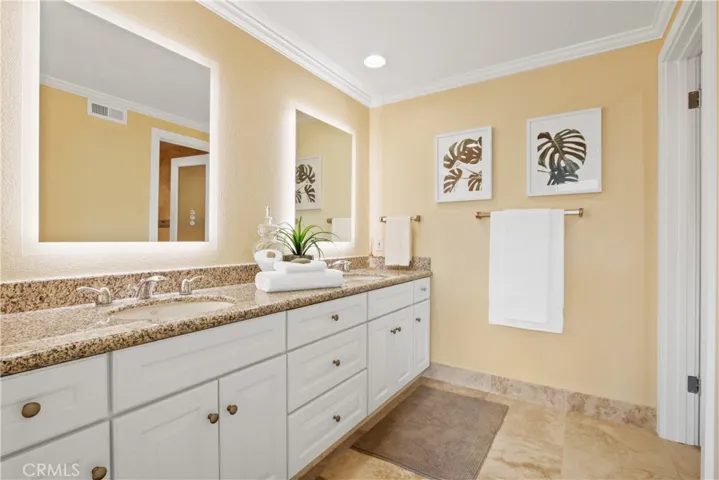 2ndary bathroom with two sinks and ideal lighting