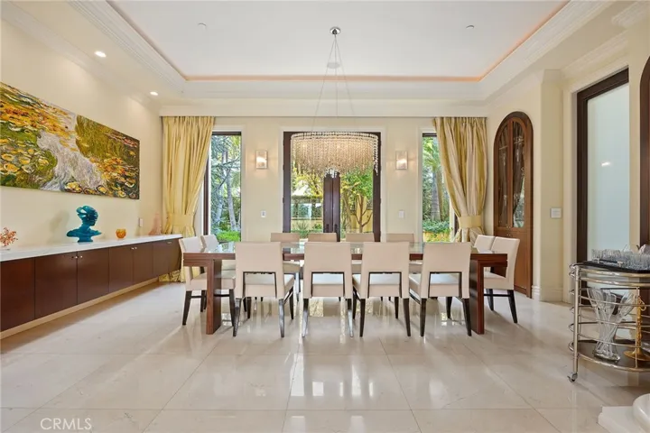 Formal Dining room with designer chandelier.  Built in display cabinets and floating shelf. View outside is a quaint reflection pond and many fruit trees.