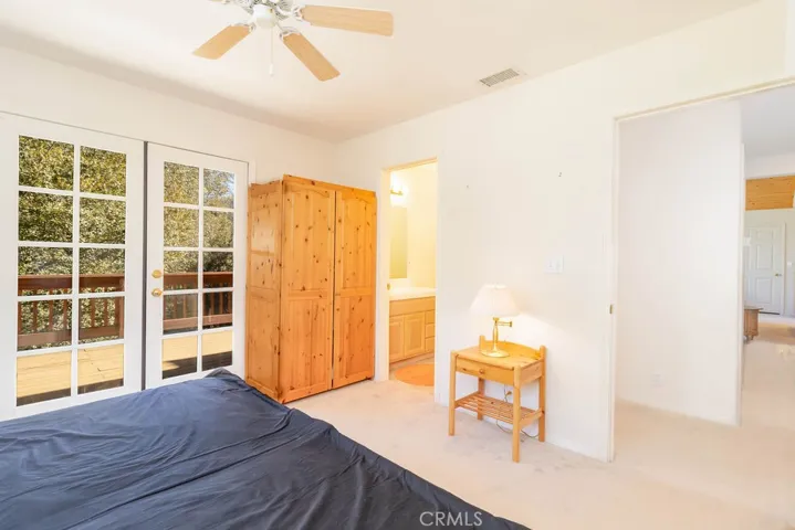 Light from French doors and the window keep the primary bedroom bright and open to the trees and mountain views.