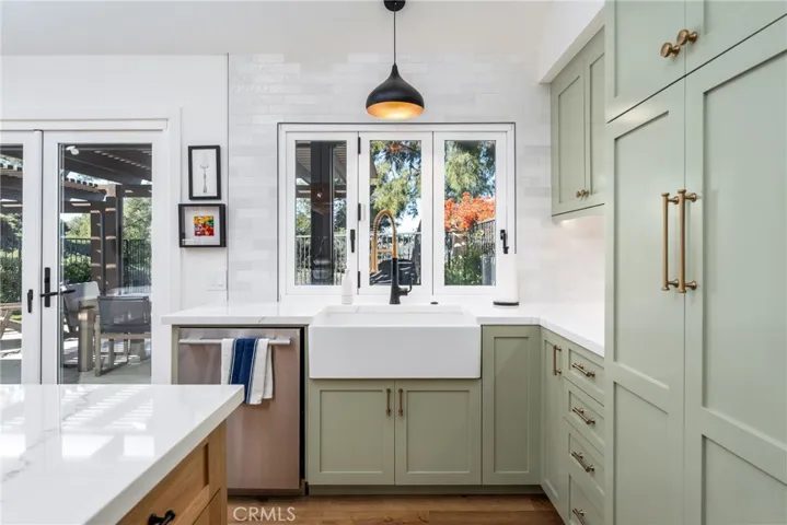 Large basin sink with high end designer fixtures and finishes. The custom fridge is hidden into the cabinetry on the right, and the tri-fold kitchen window opens onto the outdoor patio to let in the ocean breezes!