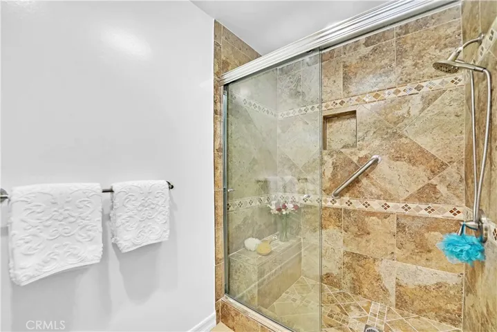 Primary Suite has Beautiful Ensuite Bathroom with Granite countertop and this Walk-In Shower with Sitting Bench, Designer Tile surround with Tile Inlay and Clear Glass Enclosure
