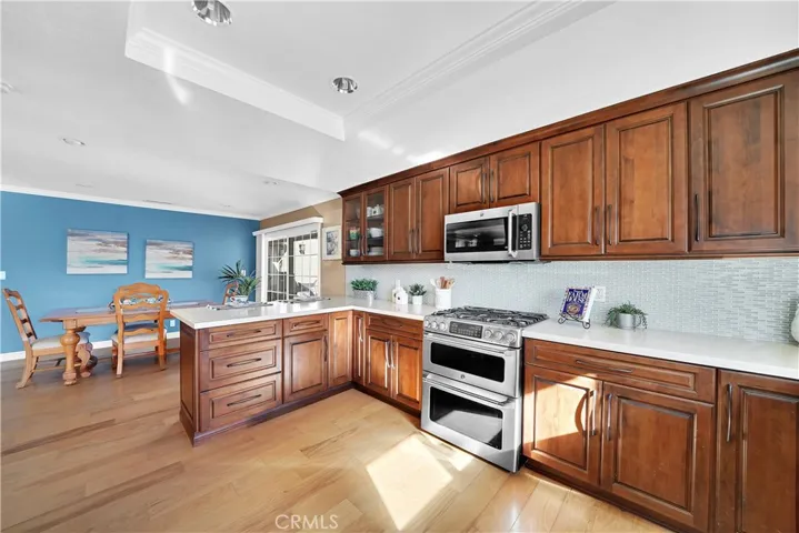 Quartz Kitchen with Breakfast Bar, Glass Mosaic Backsplash, Stainless Appliances (Gas Range w/5 Burners & Double Ovens, Bosch Dishwasher, Confection Microwave), and Custom Self-Closing Cabinetry with Lighted Glass Display Panels, Under Cabinet Lighting, Pull-Outs, Hidden Trash, and Lazy Susans.