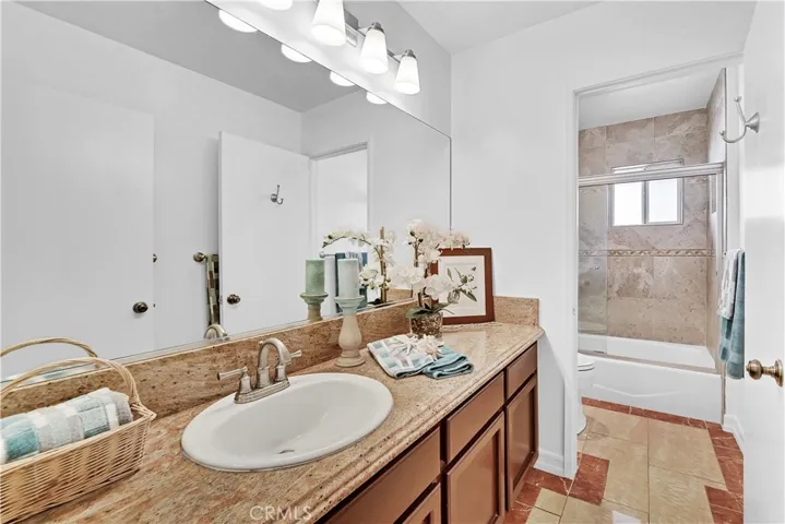 Downstairs Guest Bathroom has Granite Countertop, Tub/Shower Combo with Designer-Tiled Surround and Clear Glass Enclosure, Marble-Type Tile Flooring, and Newer Fixtures