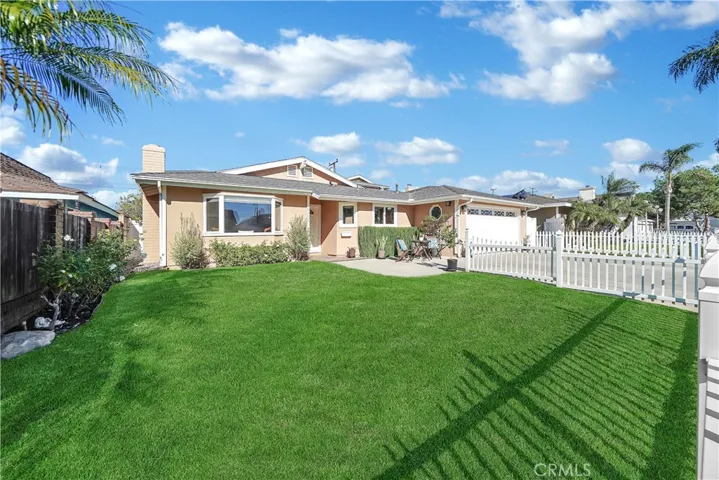 Gorgeous Curb Appeal with White Picket Fence, Lush Lawn, Manicured Landscaping, and Welcoming Front Patio