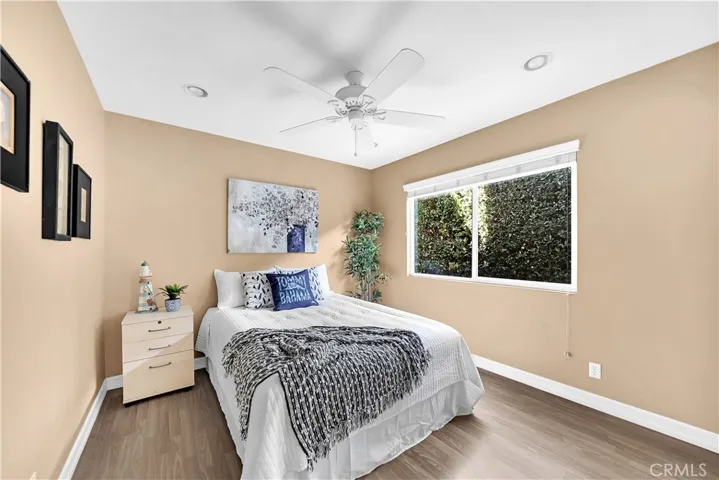 Downstairs Unit Bedroom with Wood Laminate Flooring, Recessed Lighting, Ceiling Fan, Dual Pane Window, Custom Blinds, and Mirrored Closet